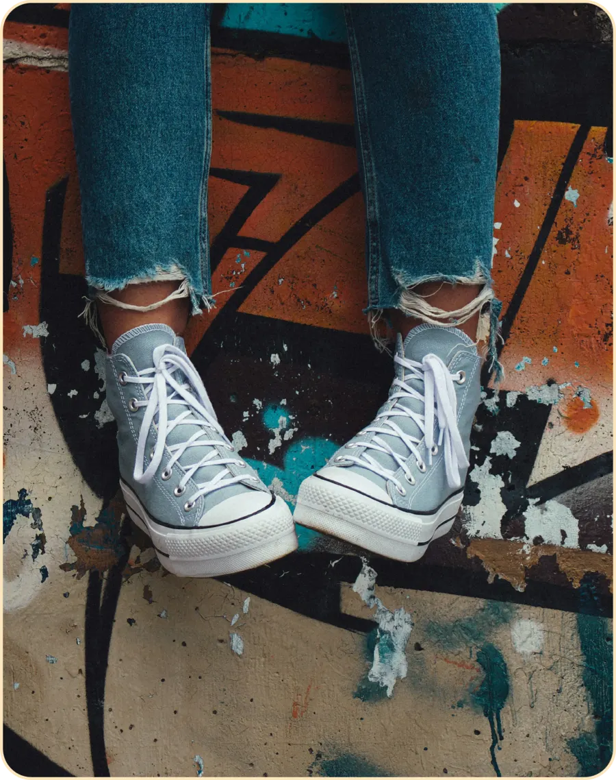 Adolescente sentado con zapatillas sobre un muro con grafiti, terapia para adolescentes en Sevilla